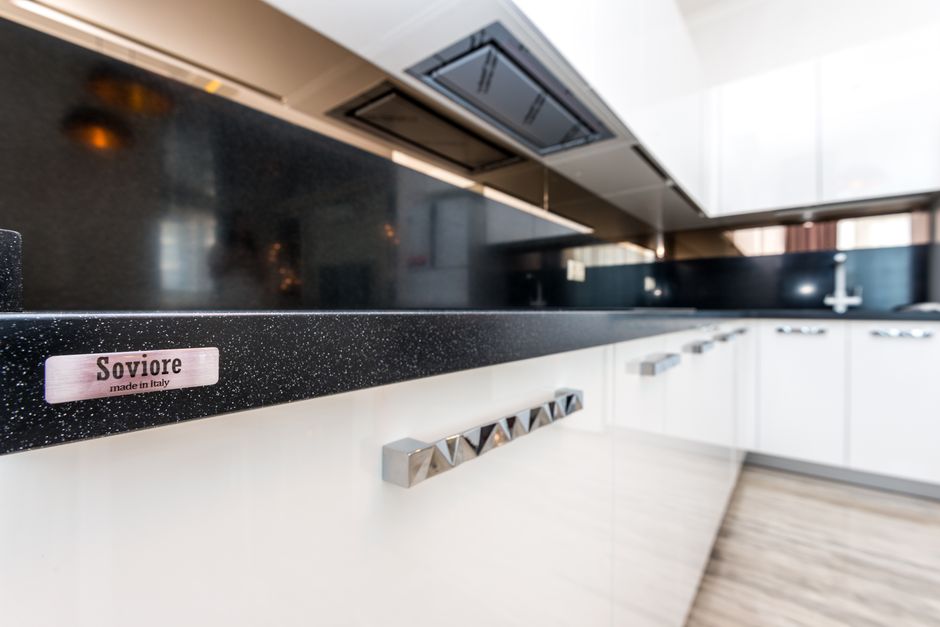 Modern kitchen with white cabinets and a stone countertop.
